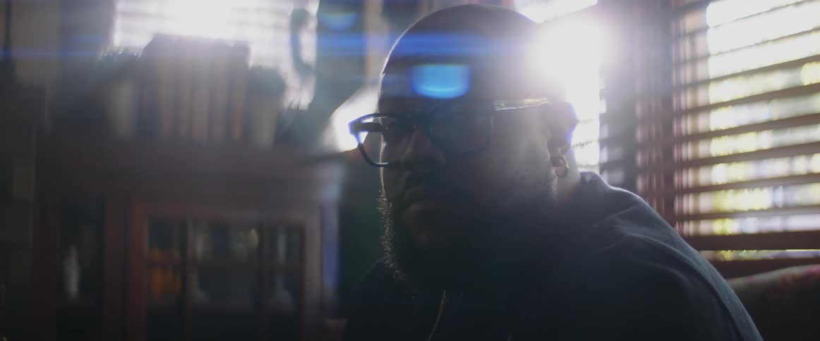 Light glare shines from near window as man sitting near window turns his head to stare