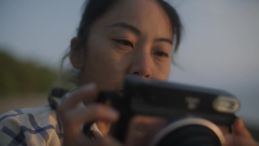 Woman raises instax camera to take a picture