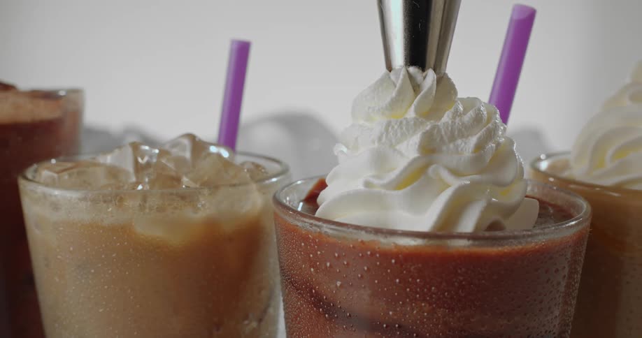 Close up of cream being poured over iced beverages on a studio