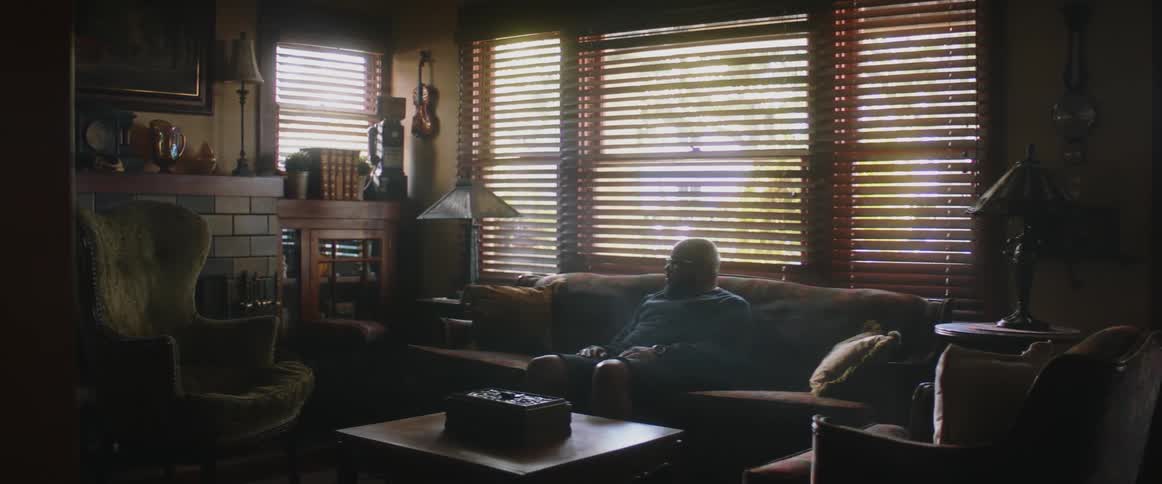 Man sitting comfortably on a couch in a cozy living room near a the windows at daytime