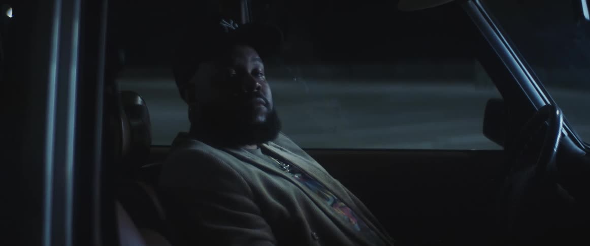 A man sitting in the drivers seat of an automobile sleeping and then he looks to his side