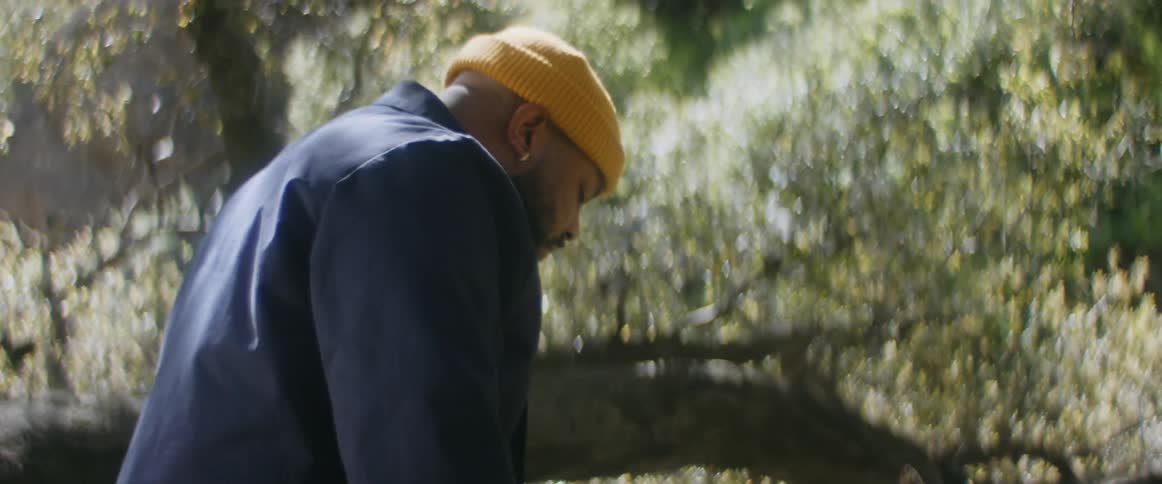 Bearded man wearing a yellow cap slowly walking around on the forest