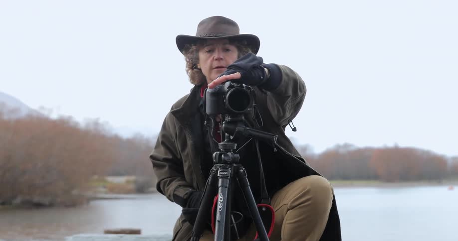 Woman adjusts camera to take pictures in nature