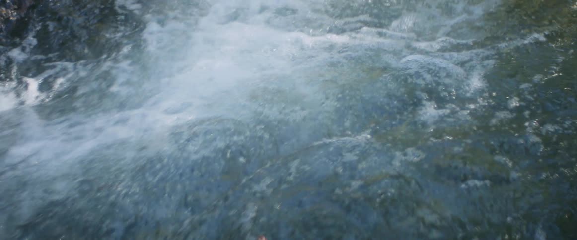 A close up of a river rapidly flowing creating bubbles on the surface