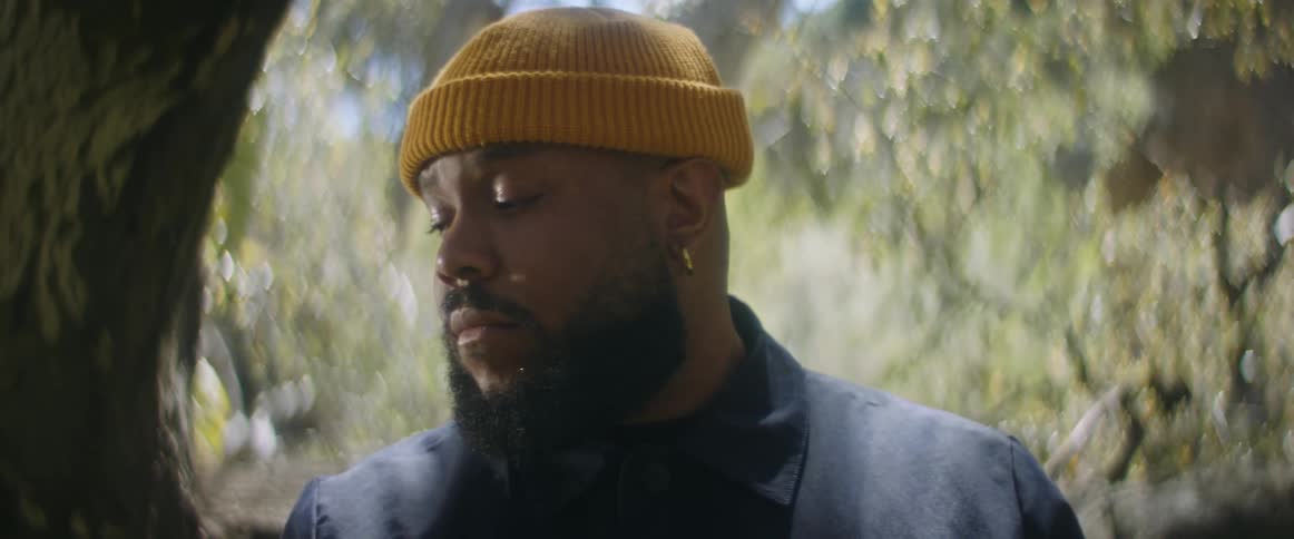 Man with yellow beanie earrings and beard in the forest