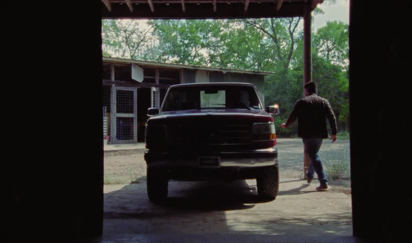 Man closes hood of pickup truck and gets in the vehicle