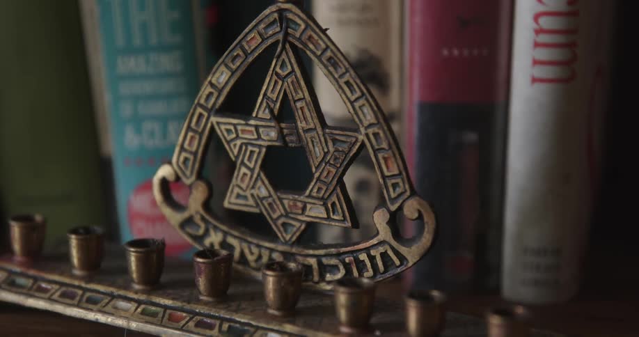 The hanukka candle is in front of the books