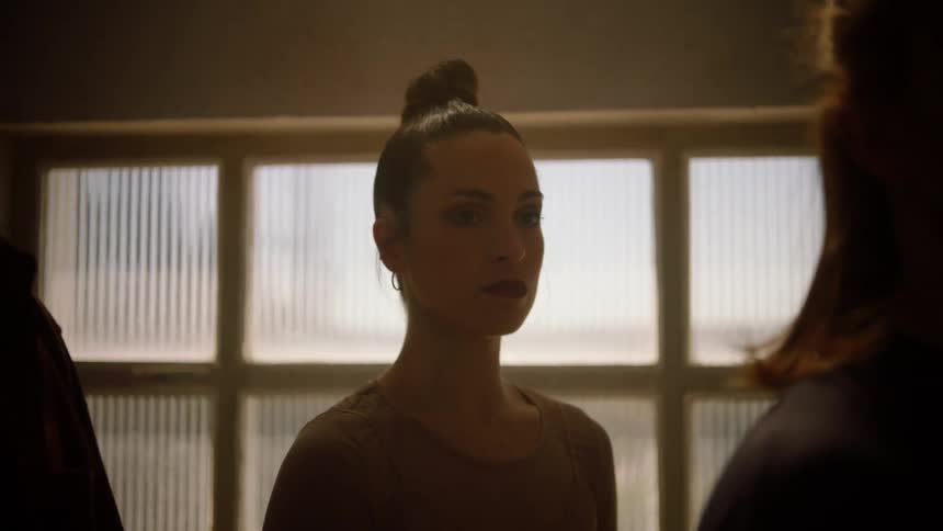 A woman dancer standing in front of a window staring ahead of her and not moving
