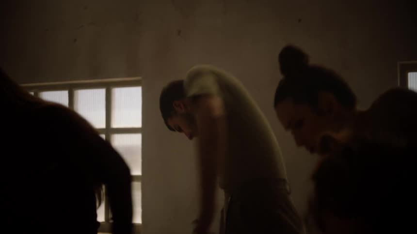 A man dancing around women in a large room in front of windows