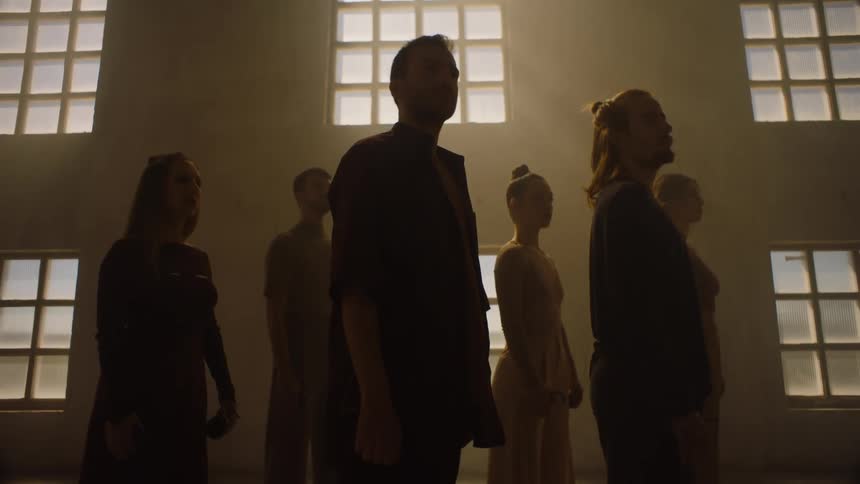 Group of six dancers standing together in studio staring upward man in front initiates dance number and the rest follow