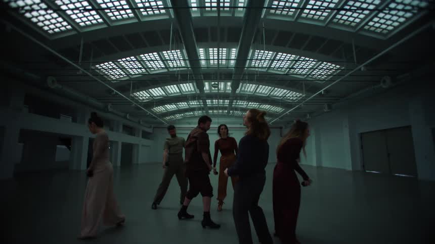 A group of dancers performing modern dance in a large finished warehouse space during the day