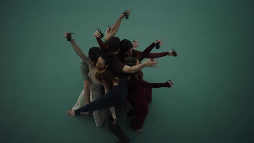 A group of people is folding themselves together in a creative manner and dancing using only their hands