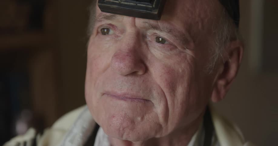 Elderly sad man looks out the windows