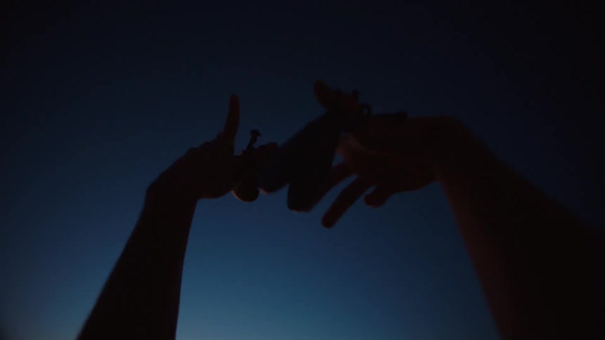 Close up of the silhouette of a couple hands holding castanets waving in the sky