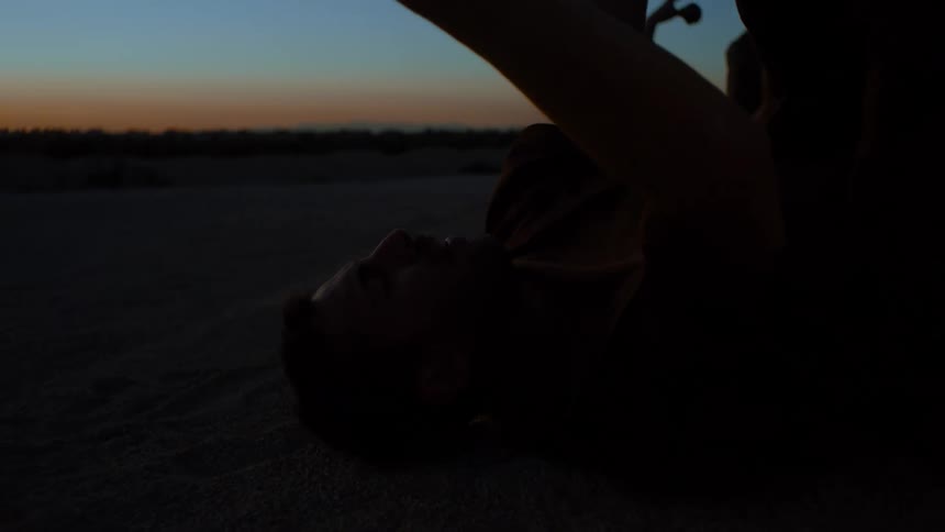 A group of people performing modern dance on the ground in the desert at sundown