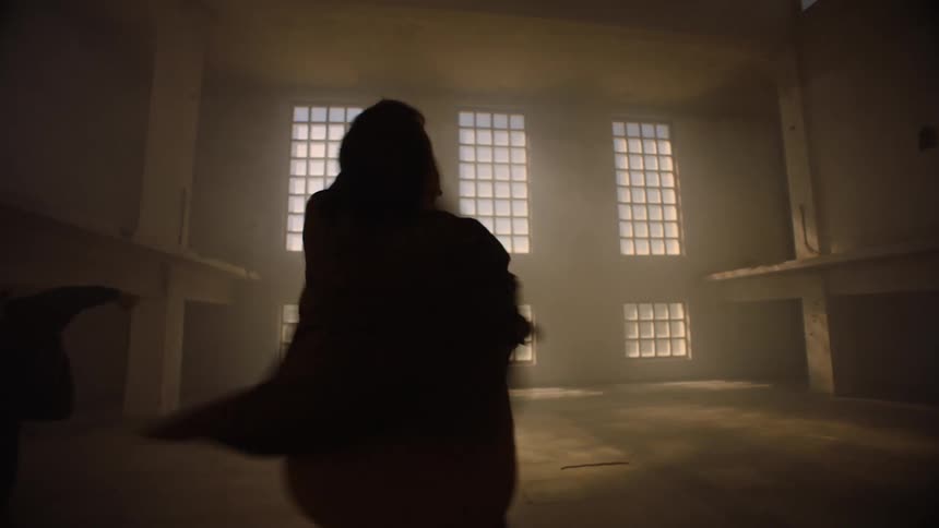 Dancers spin in dim empty roomlit from several windows