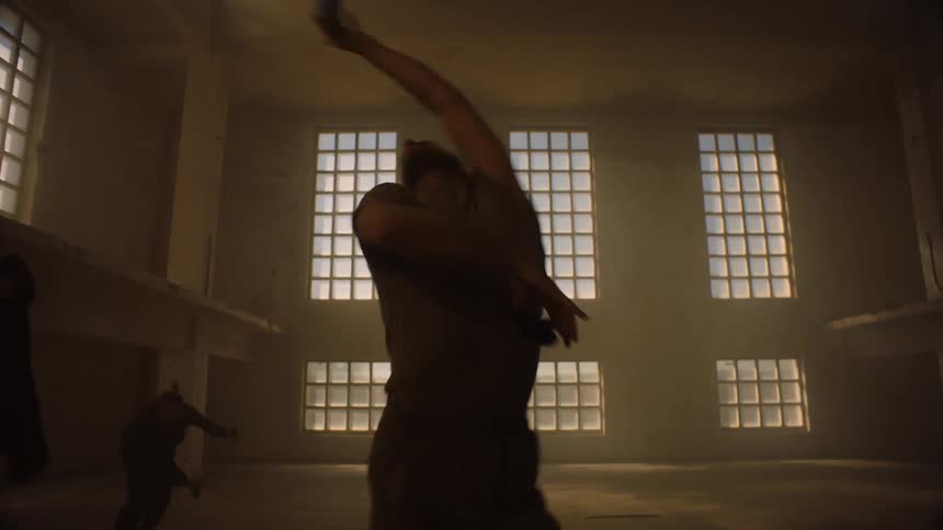 The silhouette of multiple dancers in a large empty room