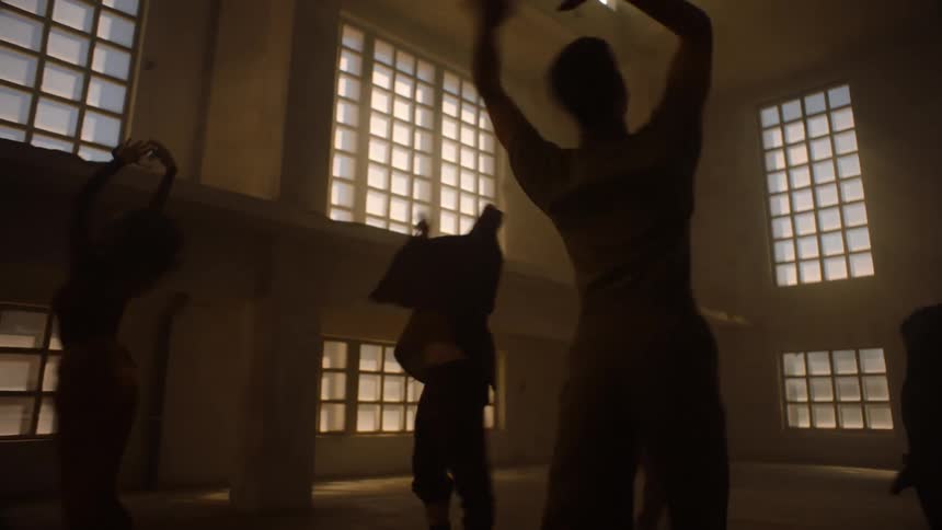 Group of dancers spin in large dimly lit room with large windows