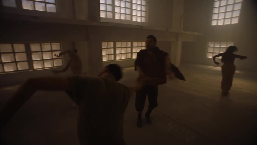 A group of people are dancing in a room with their arms in the air as they spin around