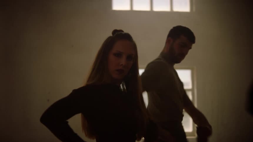 A trio of dancers move their arms in unison while dancing indoors