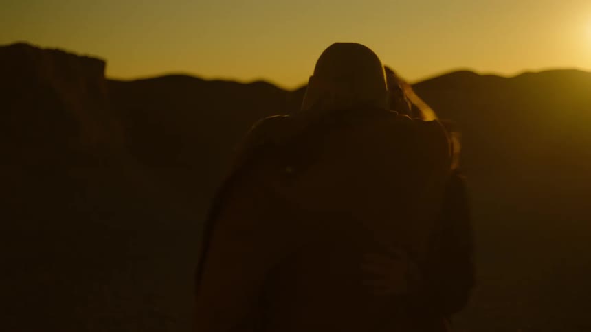 A man playfully wraps his arm around a woman and spins her away from him