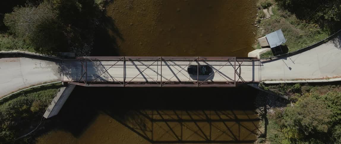 An overhead shot of an electric vehicle driving across a bridge