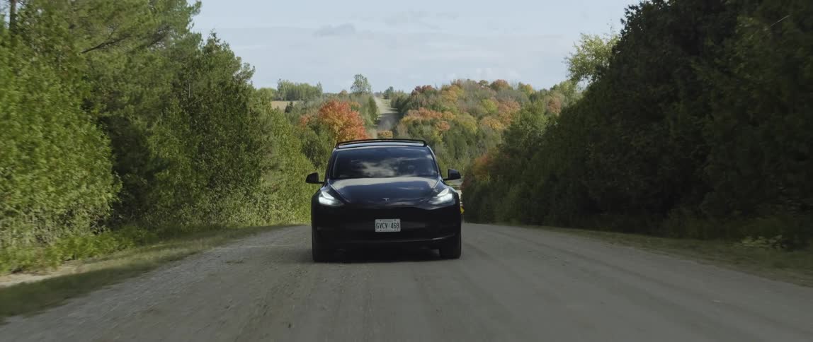 Black electric car drives along country road