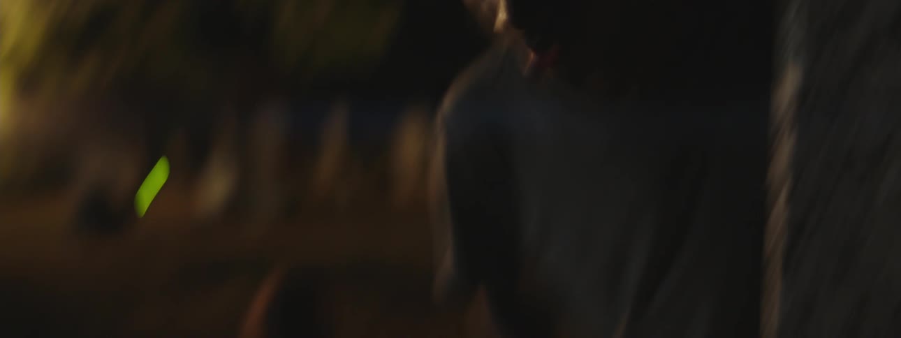 Young fearful man reclines on a grave in a cemetery at night next to a shirtless man