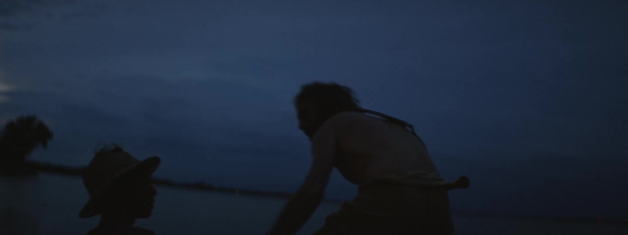 Two people sitting by the water get up and leave