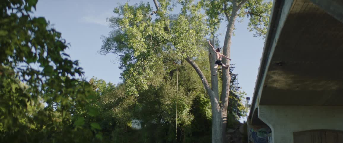 Young shirtless man jumps into a lake from a bridge at morning