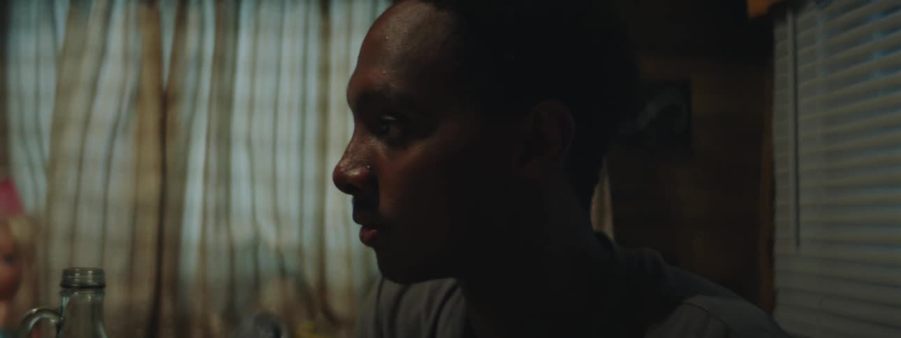 A man is lounging at a table in a mobile home and becomes startled by something
