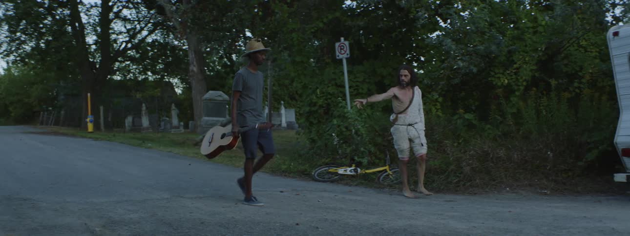 Two men with a guitar walking into a trailer