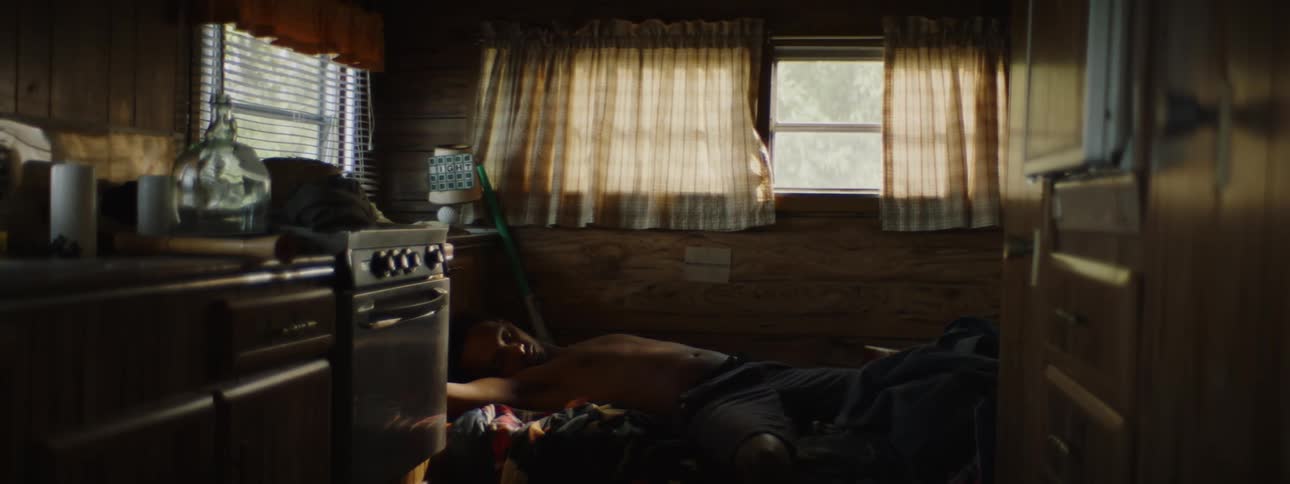 Young shirtless man sleeping on a trailer wakes up suddenly