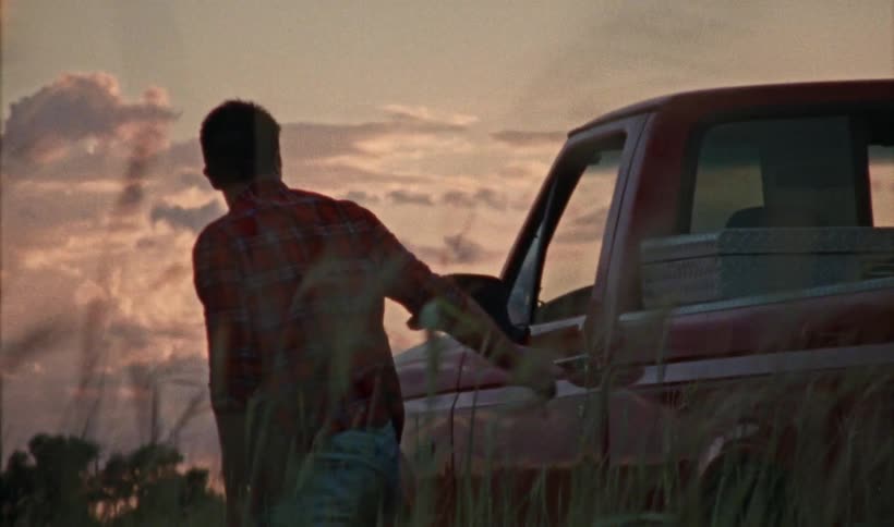 A red car comes to a stop and a man disembarks from the vehicle