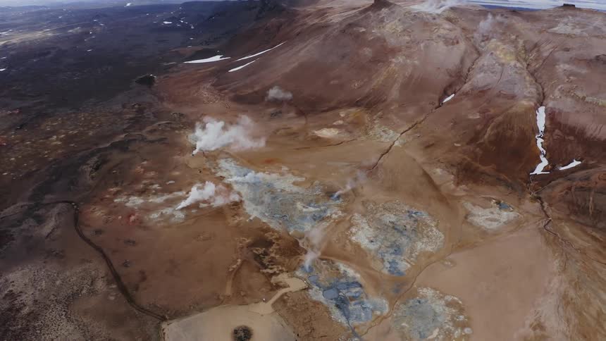 Vapor rises from ground near icy lakes and rivers near mountains