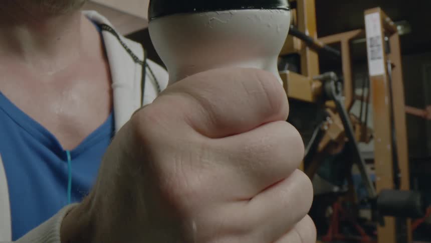 Close up of the hand of a man squeezing a strength training grip on a gym