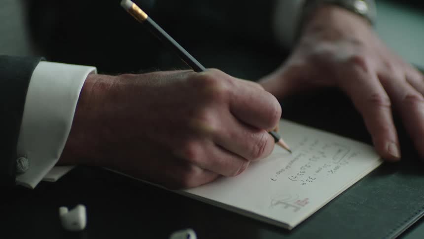 Business man taking notes with pencil and paper during a meeting