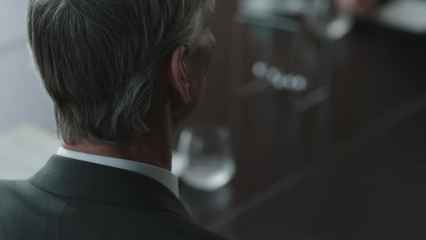 A close up of the backside of a mans head sitting very still before moving his hand