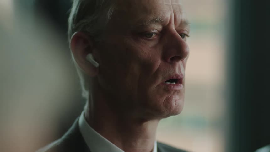 Businessman attending a meeting looks around nervously before taking his earbuds off
