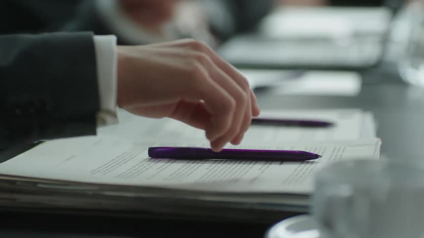 Someone picks up a pen from a table that is placed on top of a book the person then attempts to write something in the book