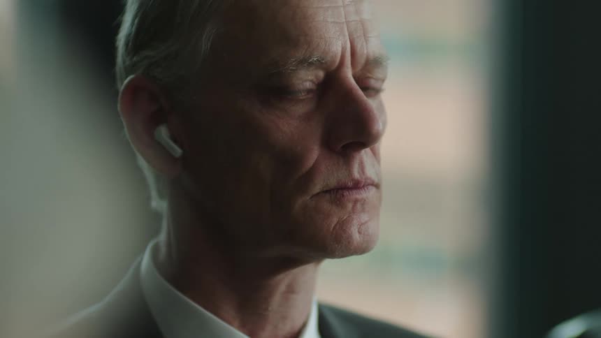 Elderly nervous businessman in suit breathes and looks around during the business meeting at the office