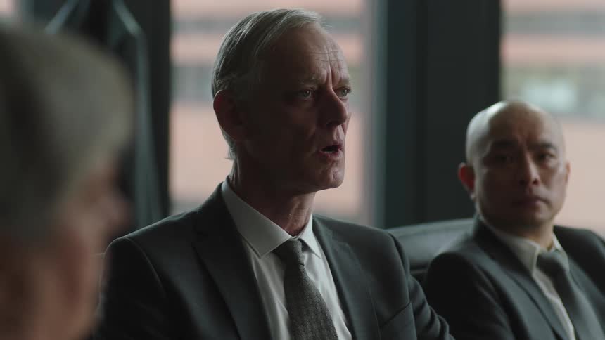 Business man looks uncomfortable and distracted while attending a board meeting in the office