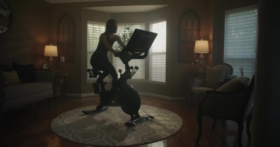 A woman is riding an exercise bike in her living room