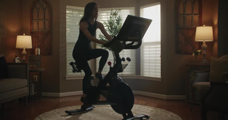A woman is riding an exercise bike in her living room