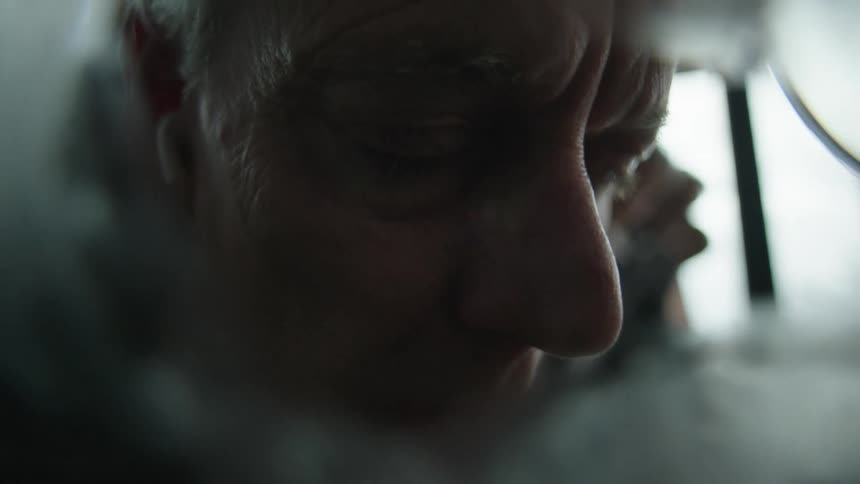 A mans reflection is shown as he peers into a mirror