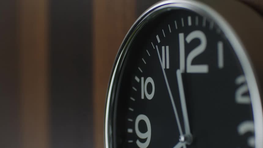 Minute hand moves across face of clock hanging on wooden wall