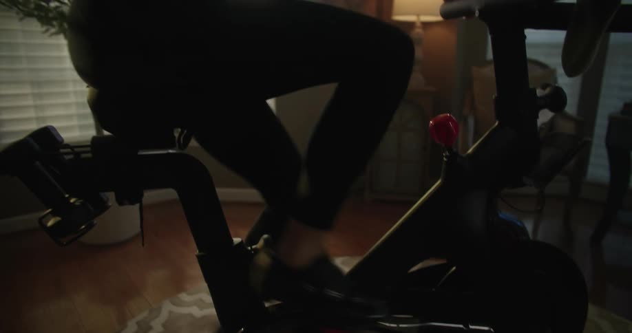 Woman pedaling on stationary bike indoors in living room