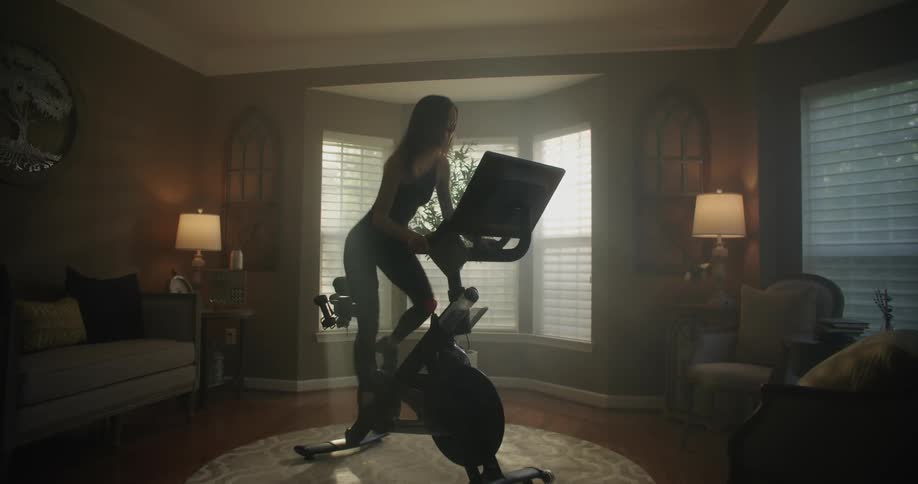 A woman exercising on a stationary bike in the middle of a living room
