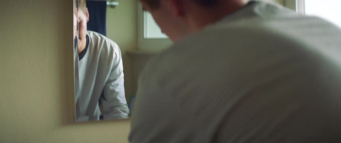A teenage boy washes his hands at a bathroom sink