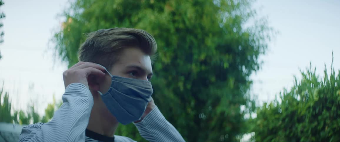 A man is putting on a face mask outdoors